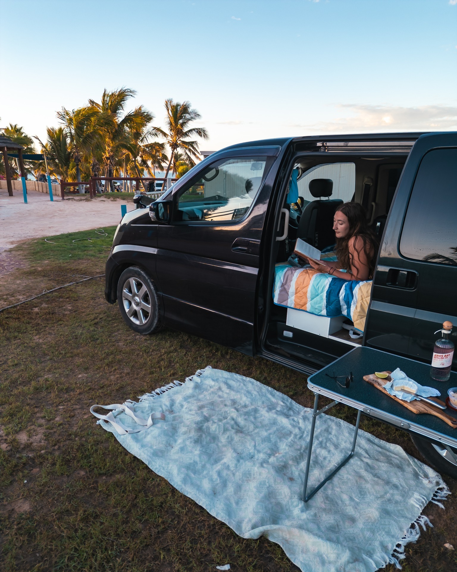 Relaxing in a plain Wicked campervan beside the beach